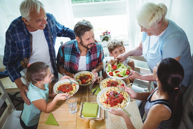 Refeição idosa do serviço da mulher a sua família imagens de stock Refeição idosa do serviço da mulher a sua família imagens de stock
