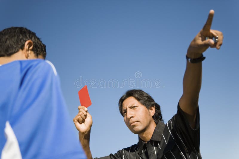 Referee holding up red card and pointing