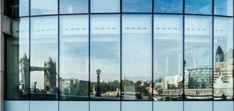 LONDON, UK - SEPTEMBER 28, 2014: The skyline of London from the Tower Bridge up to the modern buildings of the Financial District (the building of Swiss Re - aka the Gurkin - is located on the very right) is reflected in the windows of an office building on September 28, 2014 in London, UK. LONDON, UK - SEPTEMBER 28, 2014: The skyline of London from the Tower Bridge up to the modern buildings of the Financial District (the building of Swiss Re - aka the Gurkin - is located on the very right) is reflected in the windows of an office building on September 28, 2014 in London, UK.