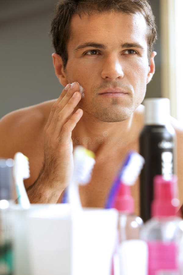 Reflection of Young Man in Mirror Applying Shaving Cream Stock Image