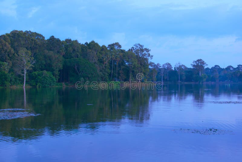 Reflections of the jungle over the broad moat of  the ancient city of Angkor Thom, in Cambodia.