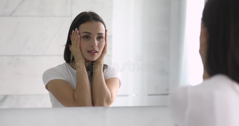 Reflet de miroir de la jeune femme heureuse touchant la peau douce.