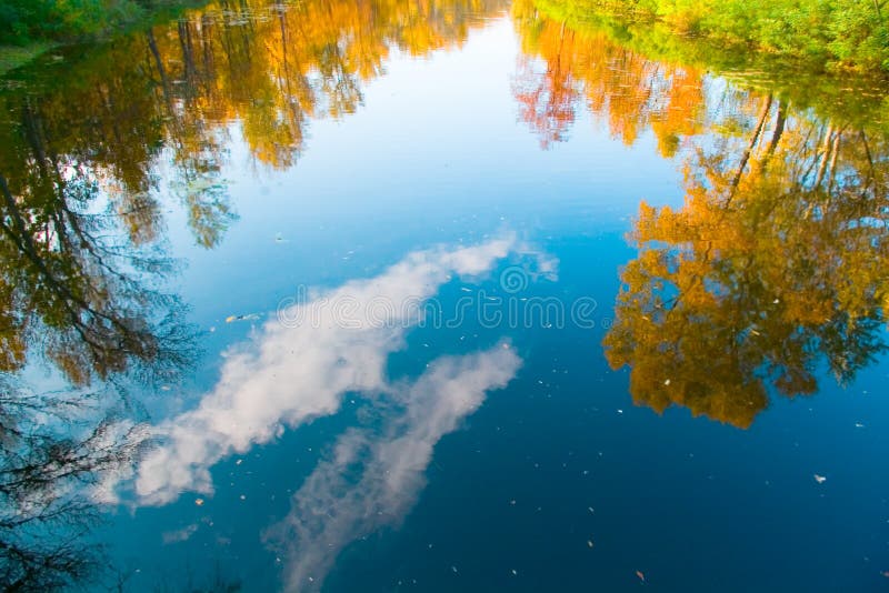 Reflexión de los árboles y del cielo, nubes del otoño en el río