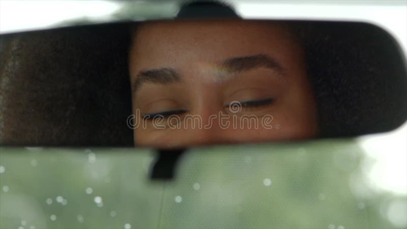 Reflexión del conductor femenino negro en el espejo retrovisor del coche almacen de metraje de vídeo
