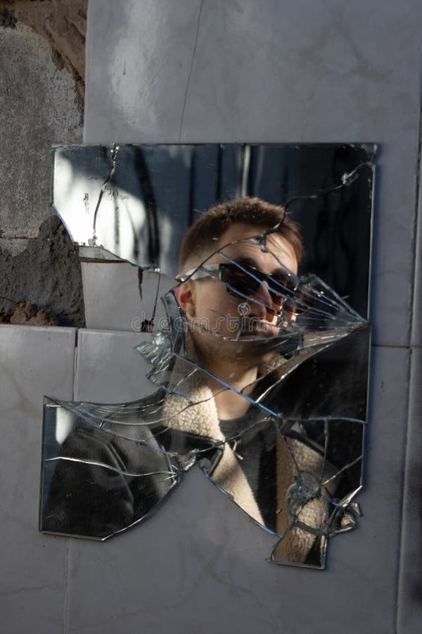 Reflexión del muchacho con las gafas de sol en un espejo quebrado foto de archivo Reflexión del muchacho con las gafas de sol en un espejo quebrado foto de archivo