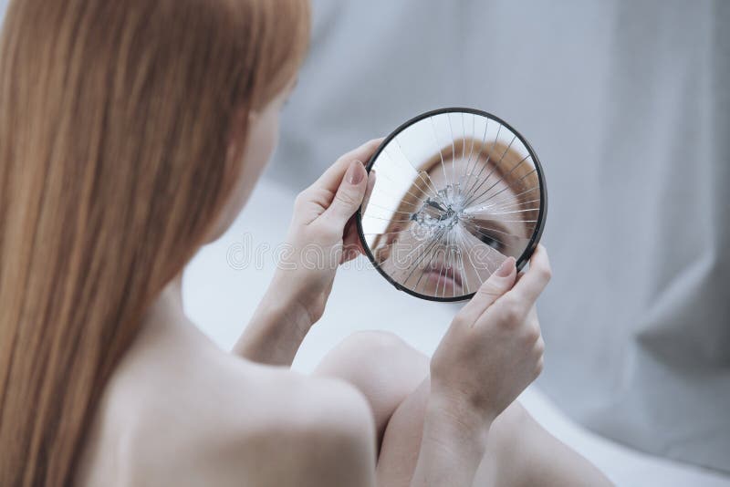 Distorted reflection of a woman in a small, broken mirror. Distorted reflection of a woman in a small, broken mirror