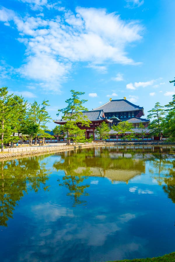 Pedestrian walkway and calm pond reflectiion of front red entry gate to Daibutsuden seen in distance on beautiful, sunny blue sky morning at Todai-ji temple in Nara, Japan. Vertical copy space. Pedestrian walkway and calm pond reflectiion of front red entry gate to Daibutsuden seen in distance on beautiful, sunny blue sky morning at Todai-ji temple in Nara, Japan. Vertical copy space