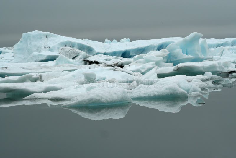 Reflexões dos icerbergs azuis e brancos de cristal na água escura preta na luz sombrio não ofuscante imagens de stock Reflexões dos icerbergs azuis e brancos de cristal na água escura preta na luz sombrio não ofuscante imagens de stock