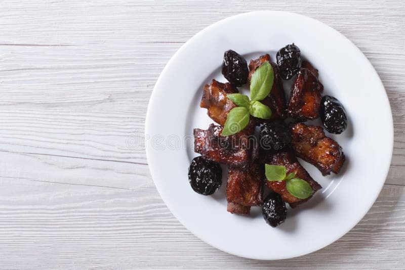 Reforços de carne de porco cozidos com ameixas secas em uma placa vista superior horizontal imagem de stock Reforços de carne de porco cozidos com ameixas secas em uma placa vista superior horizontal imagem de stock