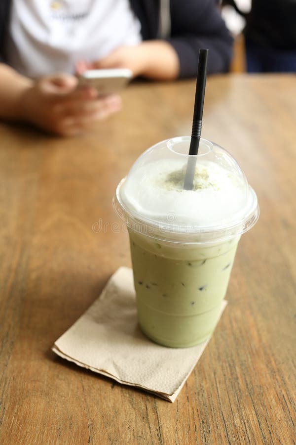 Refresque el té verde en el escritorio de madera con el fondo del café del café fotografía de archivo