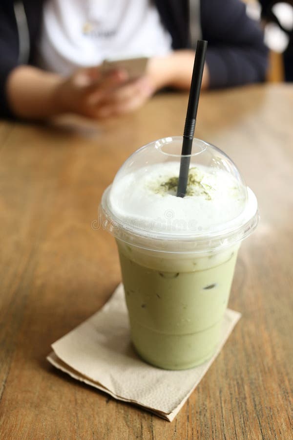 Refresque el té verde en el escritorio de madera con el fondo del café del café fotos de archivo