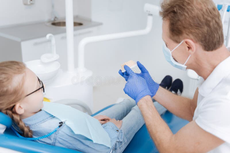 Refrigere o dentista hábil que dá uma leitura na higiene dental foto de stock Refrigere o dentista hábil que dá uma leitura na higiene dental foto de stock