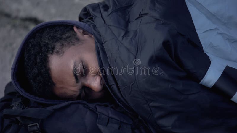 Refugiado africano en la calle cubierto con saco de dormir, sin hogar fotos de archivo libres de regalías