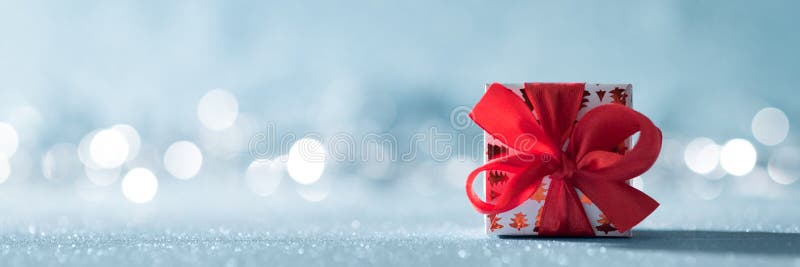 Regalo rojo hermoso de la Navidad con el arco grande en fondo azul brillante y luces de la Navidad defocused en el fondo imágenes de archivo libres de regalías Regalo rojo hermoso de la Navidad con el arco grande en fondo azul brillante y luces de la Navidad defocused en el fondo imágenes de archivo libres de regalías