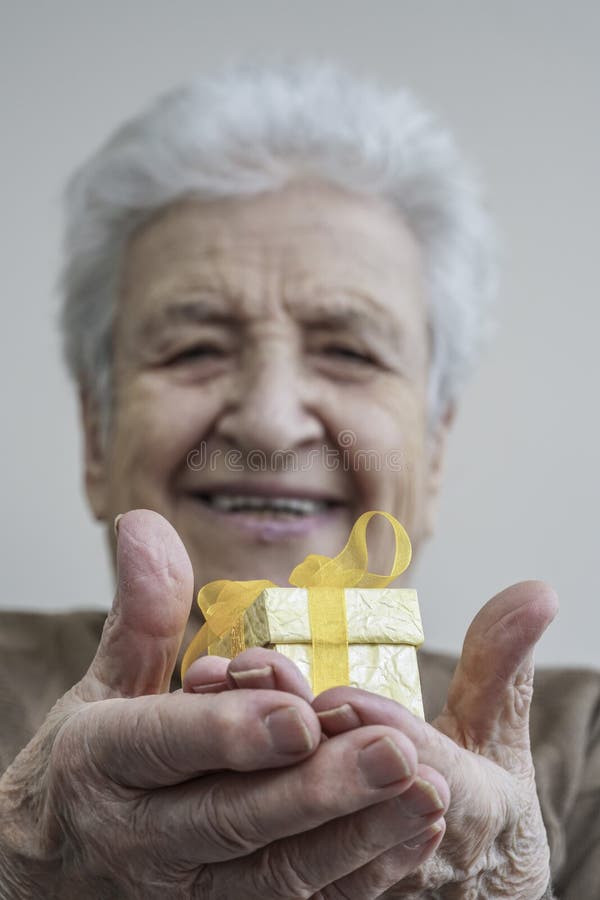 Regalo senior felice della tenuta della donna sulle sue mani immagini stock Regalo senior felice della tenuta della donna sulle sue mani immagini stock