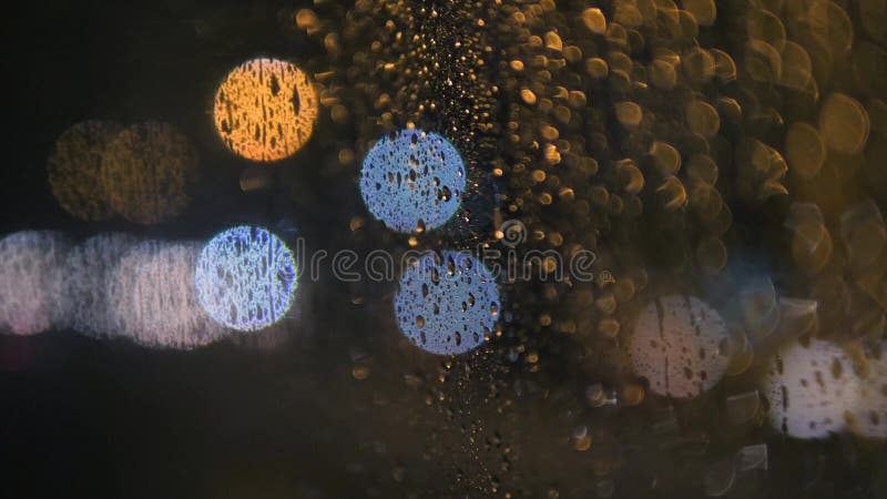Regen-Wasser fällt auf Bus-Fenster-Glas am regnerischen Tag mit unscharfem Nachtstadt-Verkehr als Hintergrund 4K