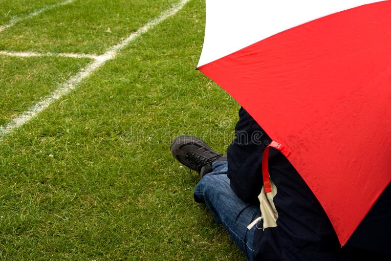 Man under the umbrella, rainy day, sports ground. Man under the umbrella, rainy day, sports ground