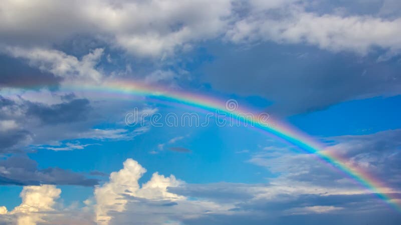 Regenboog over blauwe hemel met wolken stock afbeelding Regenboog over blauwe hemel met wolken stock afbeelding