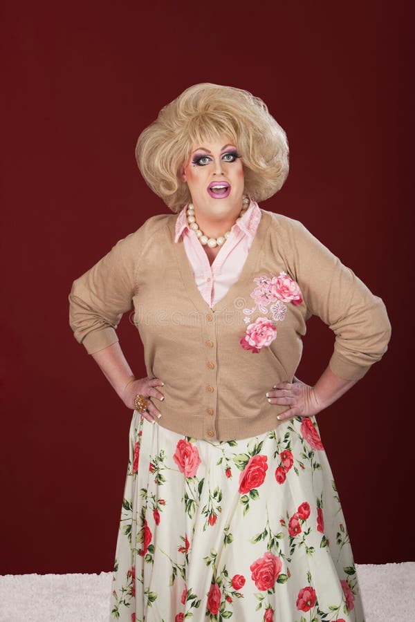 Smiling drag queen with hands on hip over maroon background. Smiling drag queen with hands on hip over maroon background