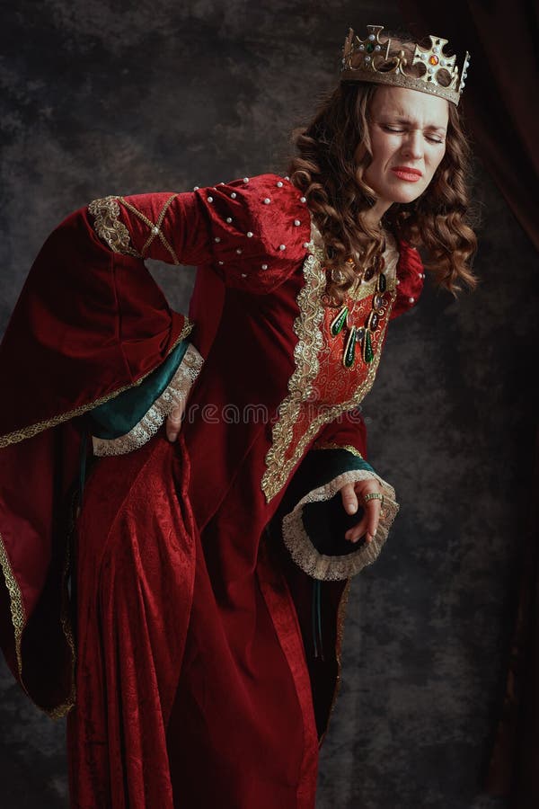 Regina medievale stanca vestita in rosso con la corona che ha mal di schiena immagine stock