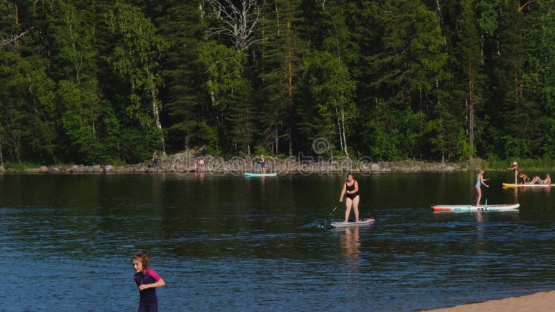 Region leningradzki rosja czerwiec 2022. ludzie kobiety mężczyźni i dzieci w strojach kąpielowych jeżdżących na deskach do gry na