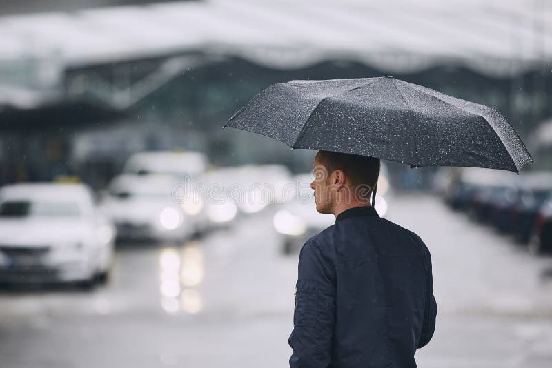 Rain in city. Young man holding umbrella walking in the street. Rain in city. Young man holding umbrella walking in the street.