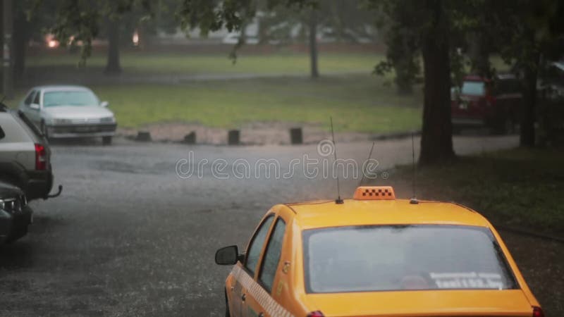 Regna att hälla på bilar och en taxi i gatan med ljudet Åska och en blixt