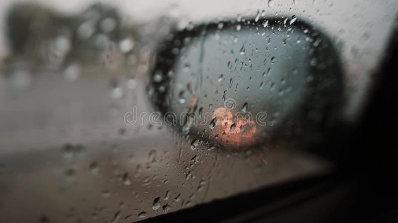 Regndroppar och reflexion av ljus på en sidospegel av en bil