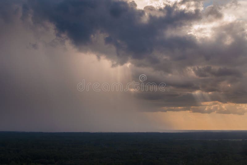 Rain pouring storming falling down on horizon with sun rays beams coming through clouds in the distance. Rain pouring storming falling down on horizon with sun rays beams coming through clouds in the distance