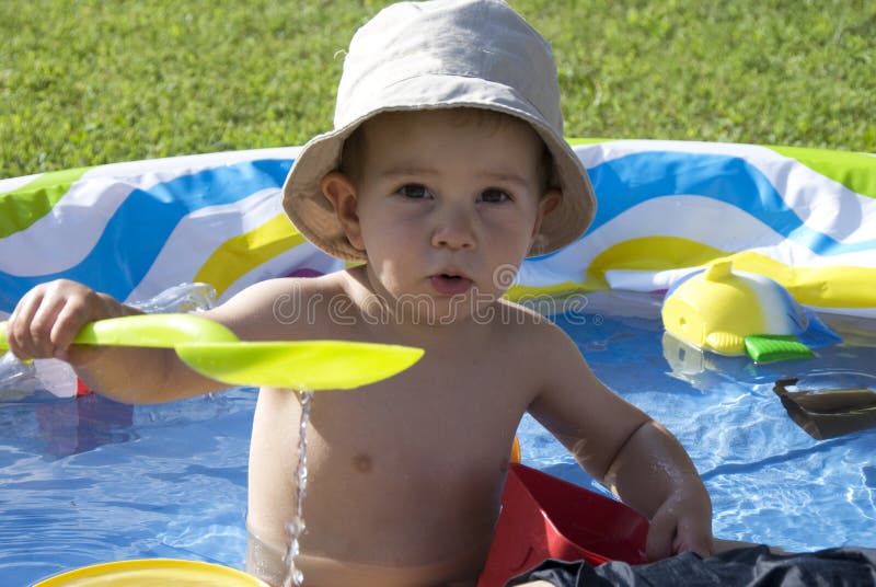 A little boy playing in the pool in his garden. A little boy playing in the pool in his garden