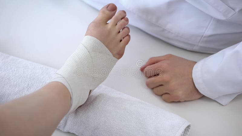 Rehabilitation specialist bandaging sprained ankle after running workout injury