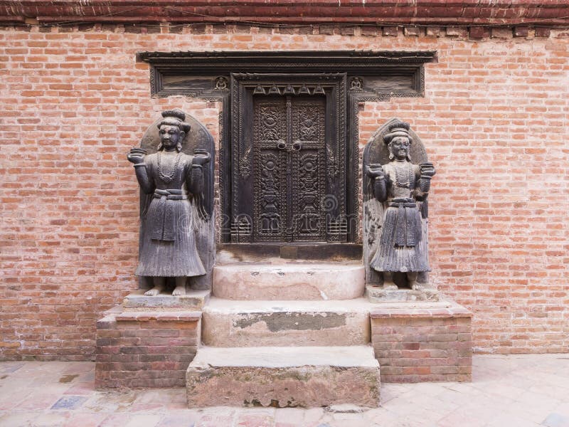 Reich geschnitzte dunkle hölzerne Tür in der traditionellen Nepaliart mit zwei schönen lebensgroßen Statuen stockfotos Reich geschnitzte dunkle hölzerne Tür in der traditionellen Nepaliart mit zwei schönen lebensgroßen Statuen stockfotos