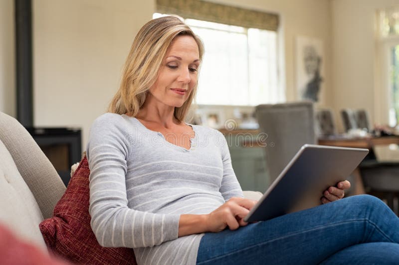 Reife Frau, die mit digitaler Tablette sich entspannt lizenzfreies stockbild