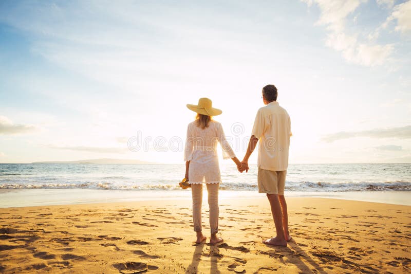 Reife Paare, die auf den Strand bei Sonnenuntergang gehen stockfotografie Reife Paare, die auf den Strand bei Sonnenuntergang gehen stockfotografie