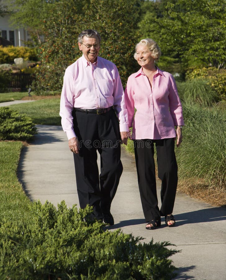 Mature Caucasian couple walking down sidewalk. Mature Caucasian couple walking down sidewalk.