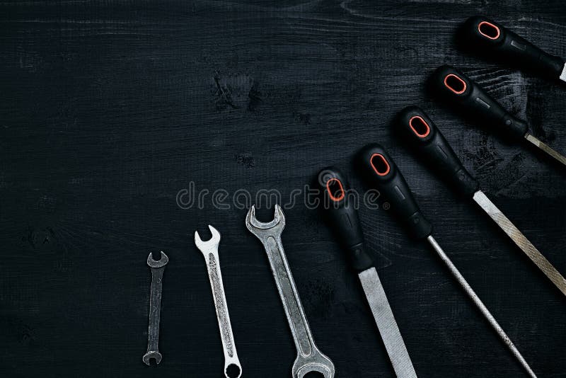 Reihe vieler scharfen Stahlblätter und Schlüssel auf schwarzem hölzernem Hintergrund