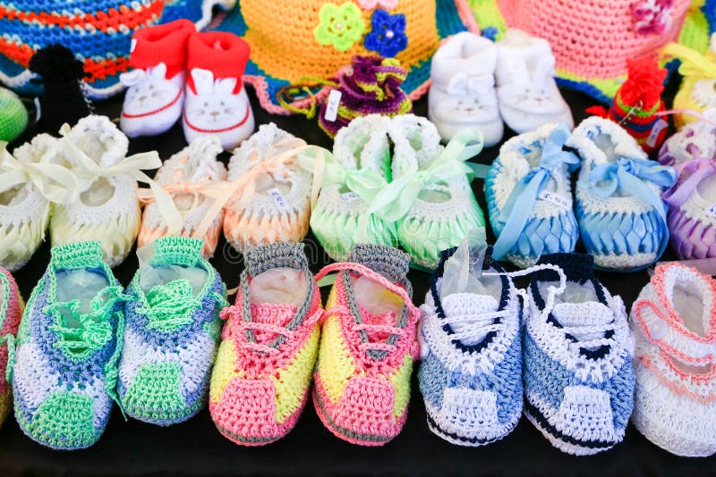 Reihen von bunten gestrickten Babyschuhen auf Schwarzem stockfotos