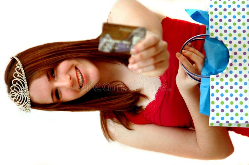 A teen girl wearing a tiara holding a shopping bag and extending credit card. A teen girl wearing a tiara holding a shopping bag and extending credit card