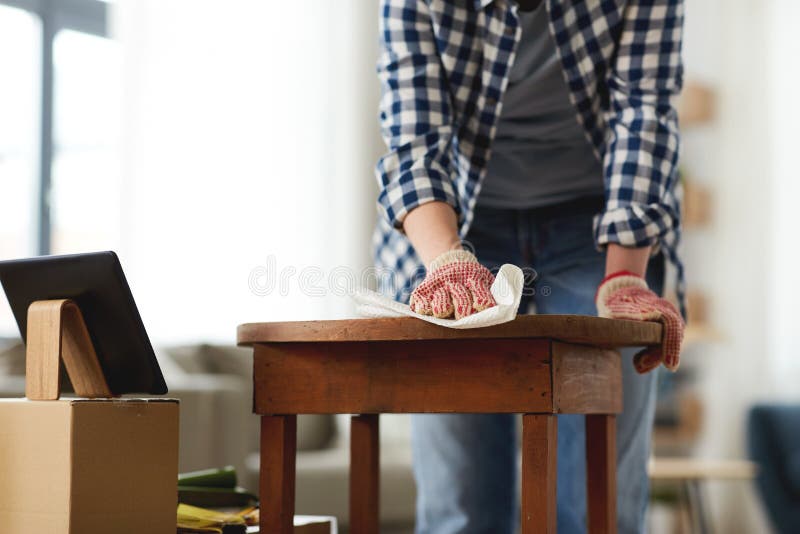 furniture renovation, diy and home improvement concept - close up of woman with tablet pc computer cleaning or degreasing old round wooden table surface with paper tissue. furniture renovation, diy and home improvement concept - close up of woman with tablet pc computer cleaning or degreasing old round wooden table surface with paper tissue