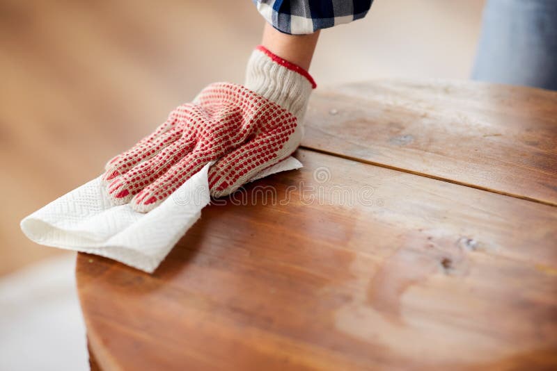 furniture renovation, diy and home improvement concept - close up of woman cleaning or degreasing old round wooden table surface with paper tissue. furniture renovation, diy and home improvement concept - close up of woman cleaning or degreasing old round wooden table surface with paper tissue