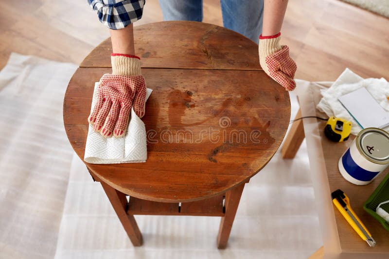 furniture renovation, diy and home improvement concept - close up of woman cleaning or degreasing old round wooden table surface with paper tissue. furniture renovation, diy and home improvement concept - close up of woman cleaning or degreasing old round wooden table surface with paper tissue