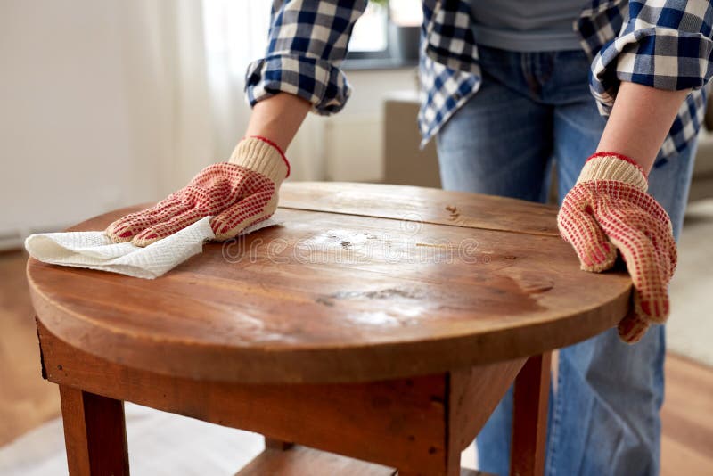 furniture renovation, diy and home improvement concept - close up of woman cleaning or degreasing old round wooden table surface with paper tissue. furniture renovation, diy and home improvement concept - close up of woman cleaning or degreasing old round wooden table surface with paper tissue