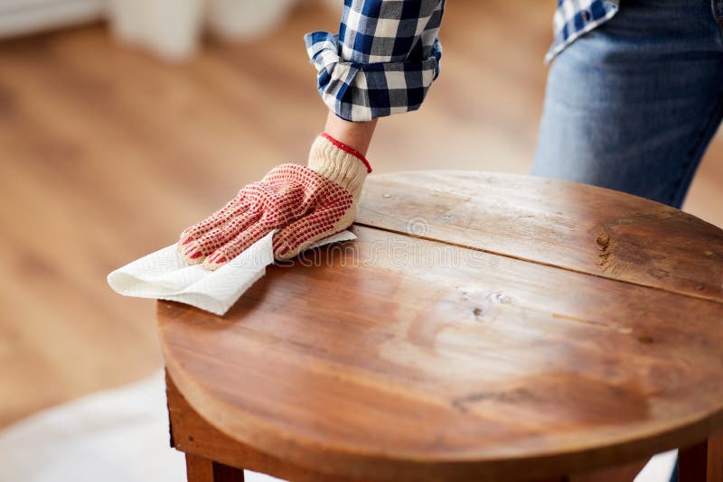 furniture renovation, diy and home improvement concept - close up of woman cleaning or degreasing old round wooden table surface with paper tissue. furniture renovation, diy and home improvement concept - close up of woman cleaning or degreasing old round wooden table surface with paper tissue