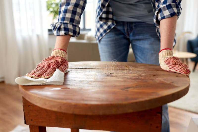 furniture renovation, diy and home improvement concept - close up of woman cleaning or degreasing old round wooden table surface with paper tissue. furniture renovation, diy and home improvement concept - close up of woman cleaning or degreasing old round wooden table surface with paper tissue