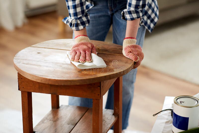 furniture renovation, diy and home improvement concept - close up of woman cleaning or degreasing old round wooden table surface with paper tissue. furniture renovation, diy and home improvement concept - close up of woman cleaning or degreasing old round wooden table surface with paper tissue