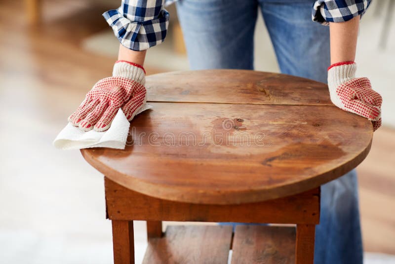 furniture renovation, diy and home improvement concept - close up of woman cleaning or degreasing old round wooden table surface with paper tissue. furniture renovation, diy and home improvement concept - close up of woman cleaning or degreasing old round wooden table surface with paper tissue