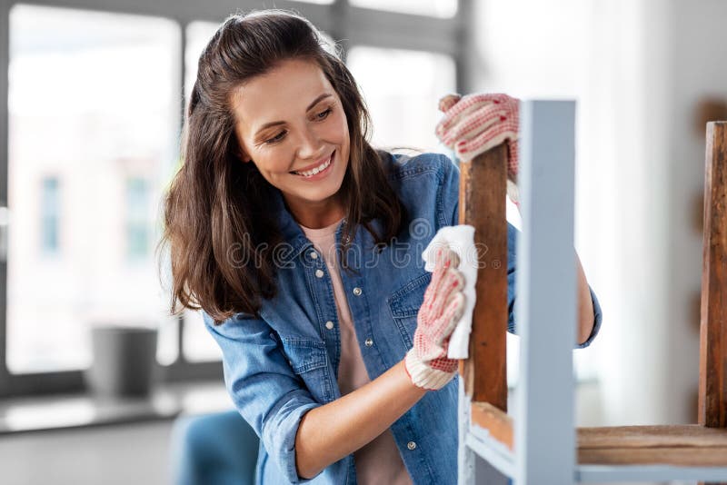 renovation, diy and home improvement concept - happy smiling woman degreasing old wooden table or chair surface with tissue. renovation, diy and home improvement concept - happy smiling woman degreasing old wooden table or chair surface with tissue