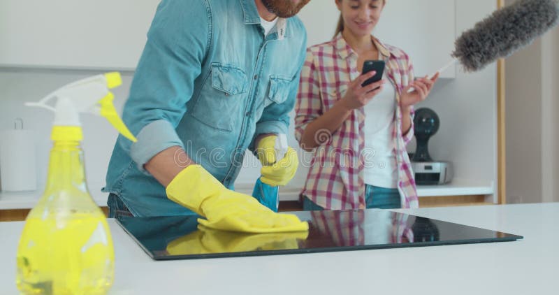 Reinigung Kochfeld Kochfeld in der Küche mit Fett Entferner Spray und ein Staub von einem Mann in Gummi-Handschuhe. weiblich
