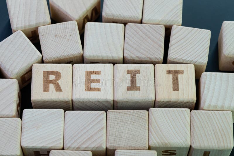 Reit, real estate investment fund concept, cube wooden block with alphabet building the word REIT on blackboard royalty free stock photos.