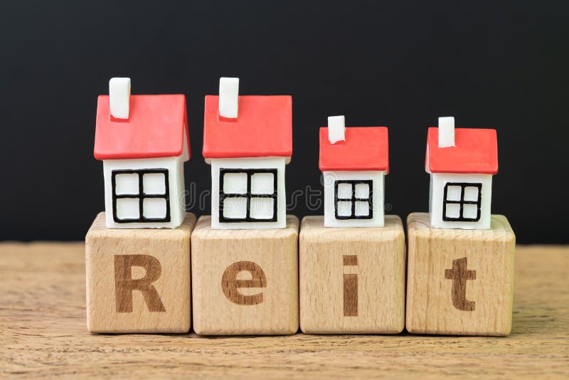 Reit, Real estate investment trust concept, miniature houses on cube wooden block with alphabet combine the word Reit on dark royalty free stock images